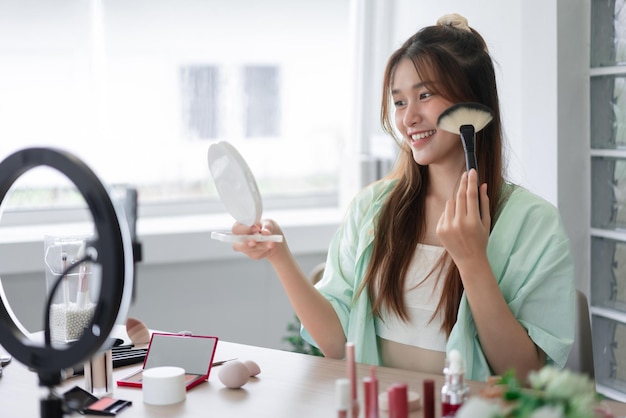 Beauty Vlogger concept Young woman use brush to applying blush on cheek and review product in Vlog