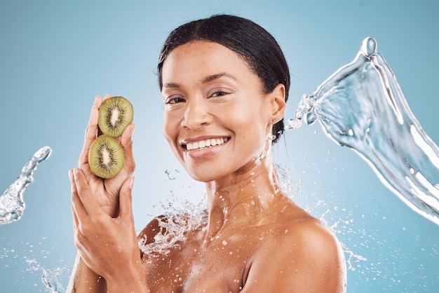 Beauty water and splash black woman with kiwi for organic cosmetic product portrait and hygiene with blue studio background Natural cosmetics and fruit with vitamin c for skin care and hydration