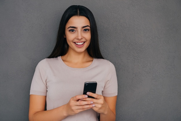 Beauty with smart phone. Attractive young woman holding smart phone and smiling