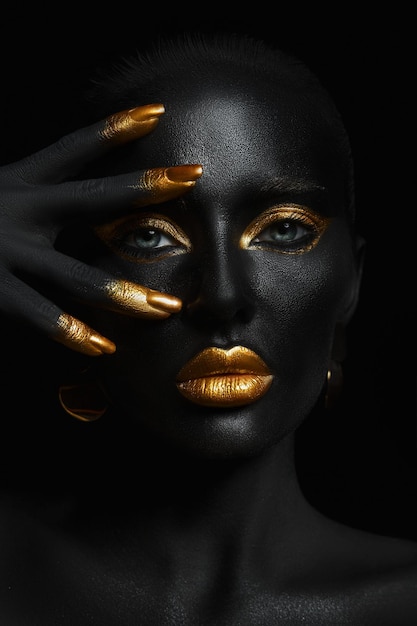 Beauty woman black skin color body art gold makeup lips eyelids fingertips nails in gold color paint Professional gold makeup