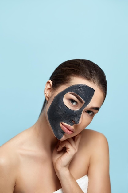 Beauty Woman Face Skin Care Mask Portrait of a Beautiful Female with a Black Mask of Clay on Face