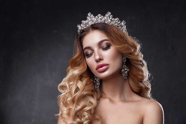 Beauty woman face with beautiful make-up colors. The image of the Queen. Dark hair, a crown on his head, clear skin, beautiful face, plump lips. 