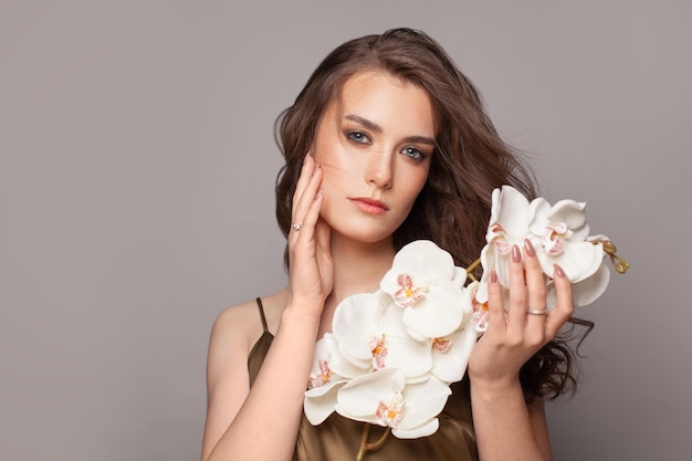 Photo beauty woman takes beautiful flowers in her hands blowing hair curly hairstyle