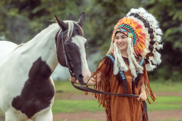 Beauty young asian girl with make up like Pocahontas, red indians woman and walking with American Paint Horse in the garden in Thailand