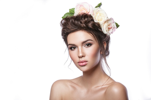 Beauty young girl, clean skin, beautiful make-up, hairstyle braids and rose flowers in hair. Light tonality on a white background.