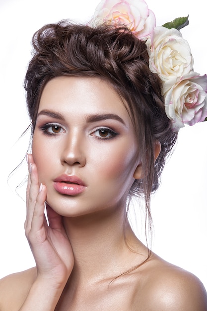 Beauty young girl, clean skin, beautiful make-up, hairstyle braids and rose flowers in hair. Light tonality on a white background.