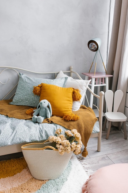 A bed in the childrens bedroom with a bunny toy and pillows Next to the bed is a wicker basket