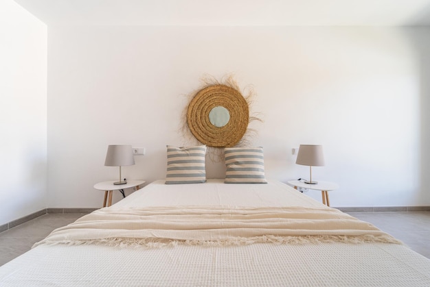 Bed in master bedroom with two pillows and two table lamps on each side in front of a white wall