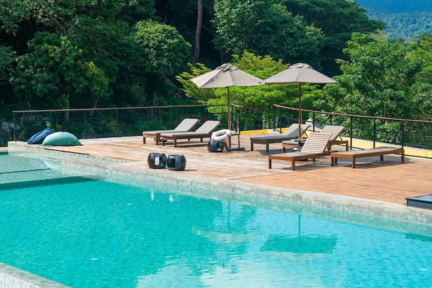 bed pool with umbrella around swimming pool with mountain and blue sky background