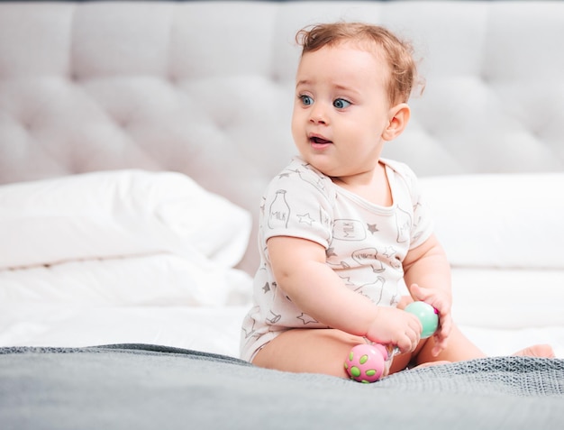 Bedroom toys and baby in home for fun playing wellness or learning for resting with comfort to relax Morning healthy boy or curious male kid sitting in house alone for child development or growth