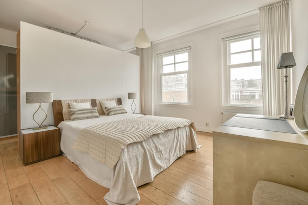 A bedroom with a large white bed on a parquet floor in a modern house