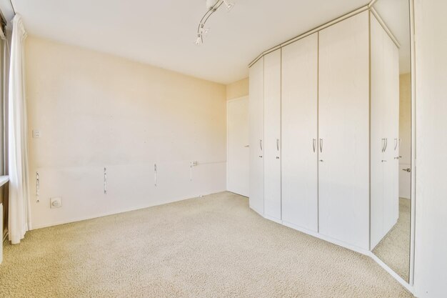 A bedroom with white cabinets and a carpeted floor