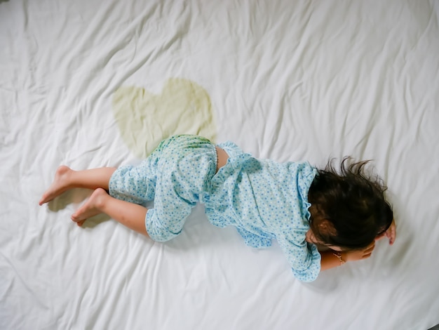 Bedwetting: Child pee on a mattress,Little girl feet and pee in bed sheet,Child development concept ,selected focus at wet on the bed