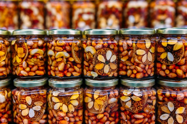 Bee honey with nuts in glass cans on counter of market