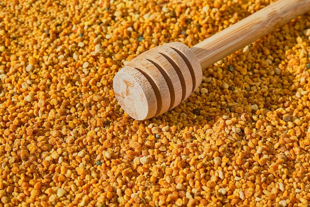 Bee pollen in granules and a spoon with a spindle closeup on environmentally friendly food supplements and health improvement Useful products idea for background or advertising