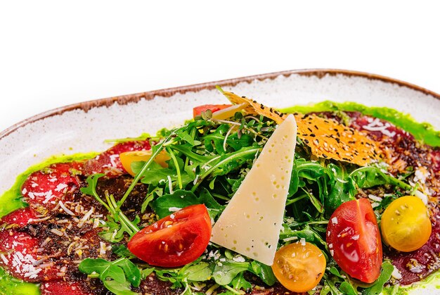 Beef carpaccio with Parmesan and arugula on plate isolated