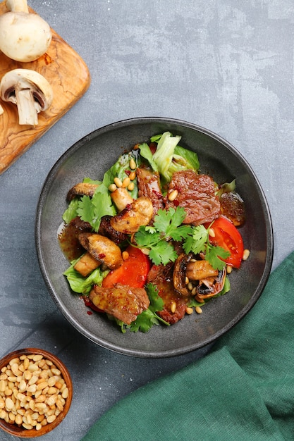 Beef and champignons with pine nuts top view. beef and mushrooms salad on concrete table.