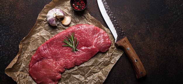 Beef lean raw fillet steak on baking paper with rosemary garlic and spices