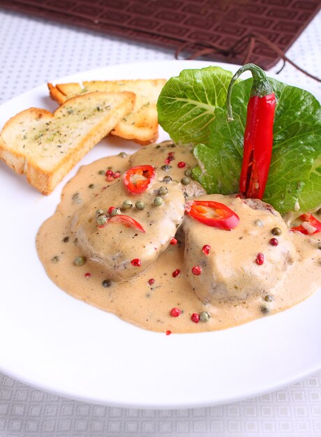 Beef in pepper sauce with croutons and salad leaves