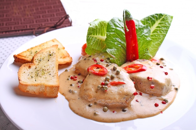 Beef in pepper sauce with croutons and salad leaves