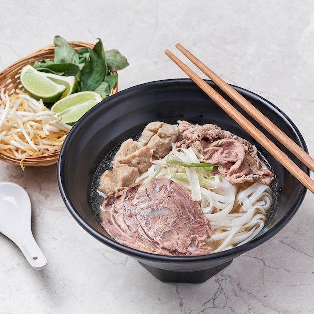 Beef Pho with noodle and lime served in a dish isolated on grey background side view of vietnam food