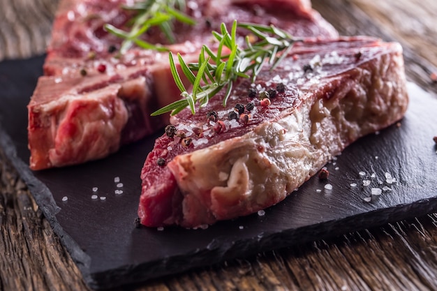 Beef raw steak. Raw fresh T-bone steak with salt pepper and rosemary.