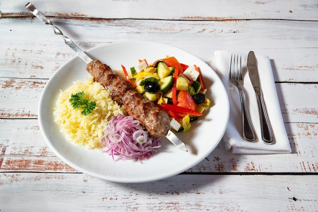 Photo beef shashlik with rice and vegetables on a plate