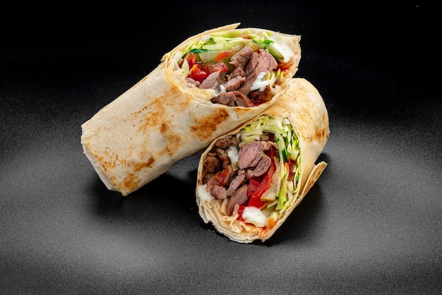 Beef shawarma on a dark background Shawarma with beef in pita bread