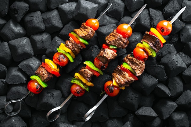 Beef skewers being grilled on a embers top view