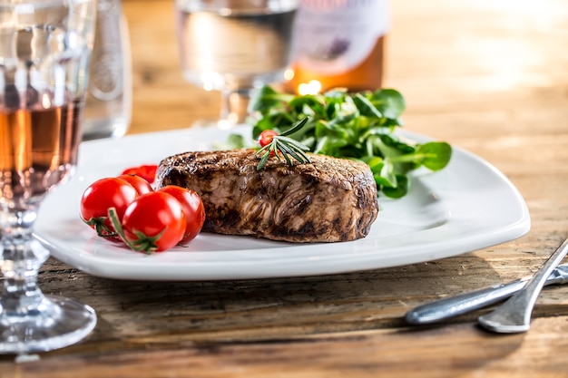 Beef Steak. Juicy beef steak. Gourmet steak with vegetables and glass of rose wine on wooden table.