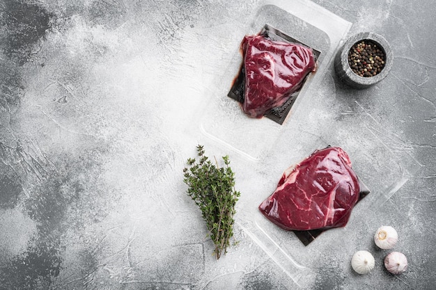 Beef steak vacuum sealed set on gray stone table background top view flat lay with copy space for text