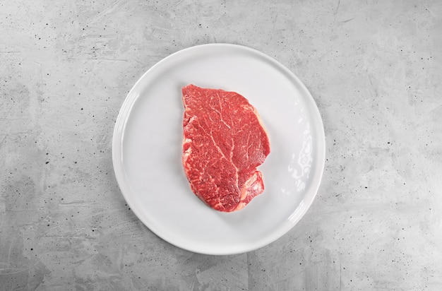 Beef steak with rosemary and pepper on a white plate with copy space