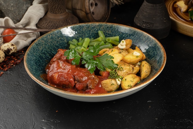 Beef in tomato sauce with baked potato slices with garlic, asparagus beans and herbs