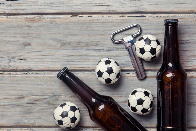 Beer bottle with soccer football balls on a wooden background