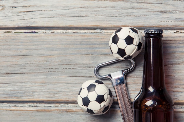 Beer bottle with soccer football balls on a wooden background