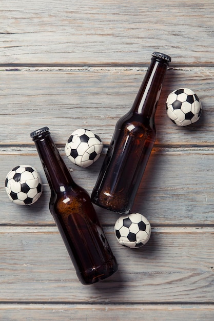 Beer bottle with soccer football balls on a wooden background