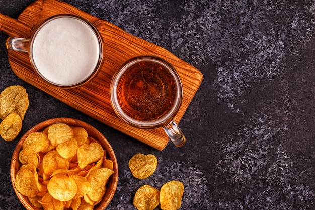 Beer and crispy potato chips on stone surface