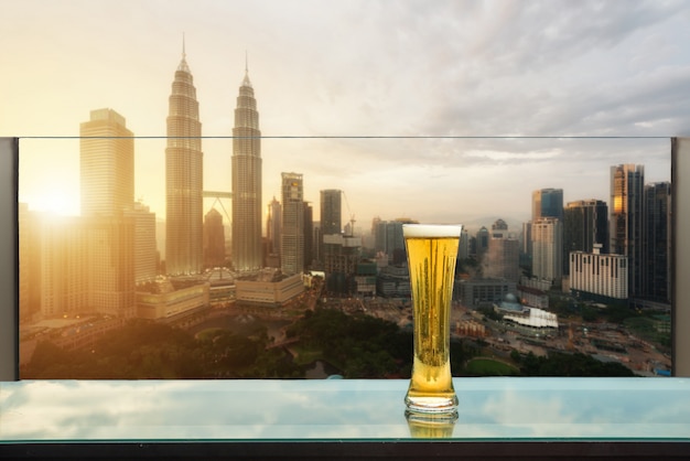 Beer and foam beer on table in rooftop bar with Kuala Lumpur, Malaysia.