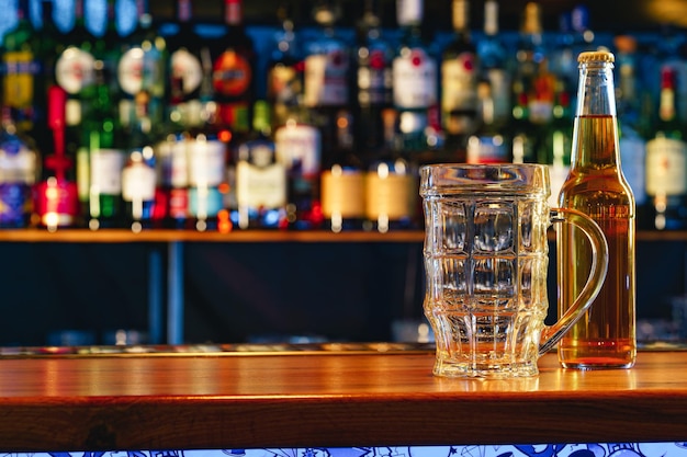 Beer glass and bottle on wooden countertop in a pub