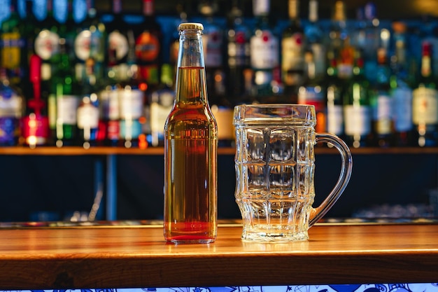 Beer glass and bottle on wooden countertop in a pub