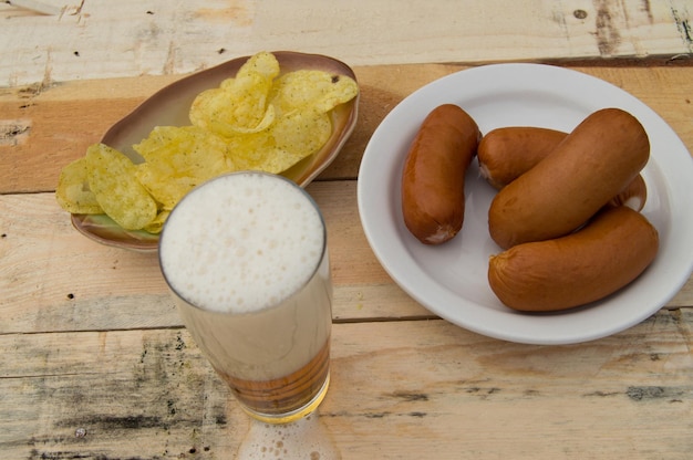 Beer in a glass with foam sausages chips on boards in the garden Oktoberfest theme