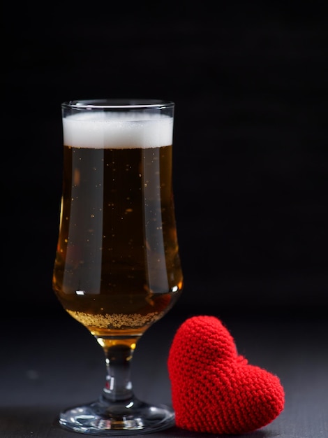 Beer love. A glass of beer on a dark background, a red heart