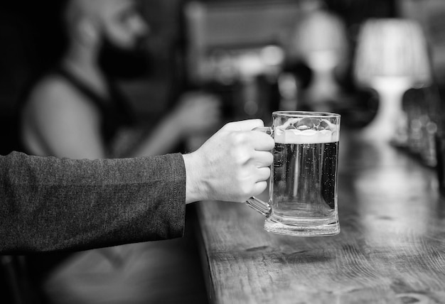 Photo beer mug on bar counter defocused background glass with fresh lager draft beer with foam male hand holds mug filled with cold tasty beer in bar friday leisure tradition beer pub concept