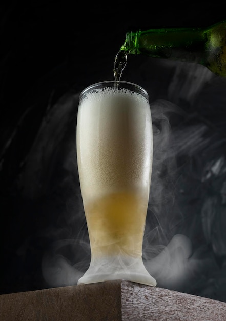 Beer pouring into cup in a bar Wooden desk and grey background