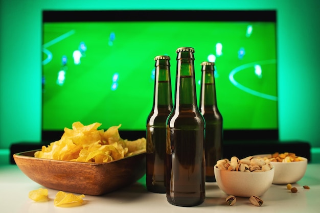 Beer and snacks set on football match tv background