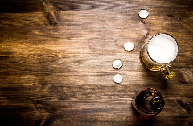 Beer style - bottle, beer in the glass and covers on wooden table