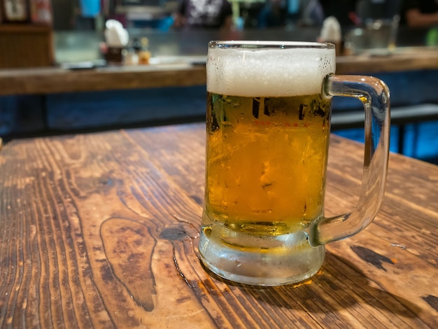 Beer with bubble level in glass on wooden table in Izakaya style restaurant