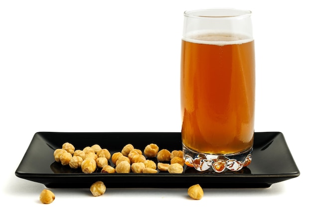 Beer with hazelnuts on a black plate.