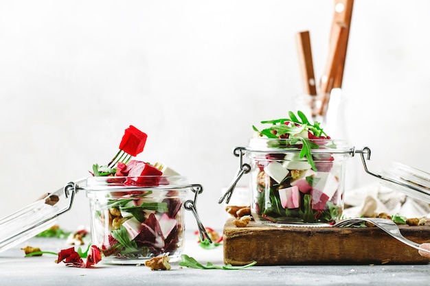 Beet and cheese healthy salad with arugula and walnuts trendy salad jar gray kitchen table place.