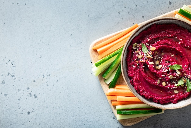 Beet hummus in a ceramic bowl on a light background, top view, copy space